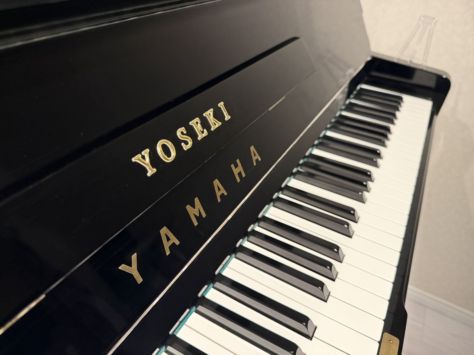 Close-up of the gold YOSEKI logo engraved on the piano, with the keyboard